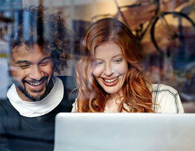 two people smiling at a laptop