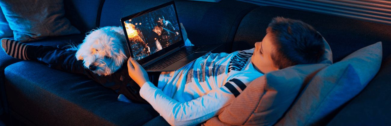 young boy watching a movie on his computer with a dog on his lap