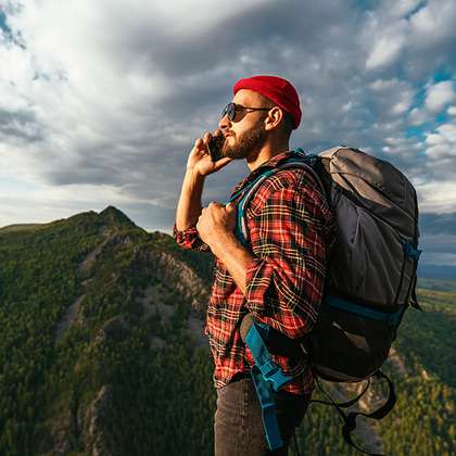 Man uses mobile phone while hiking in mountain wilderness