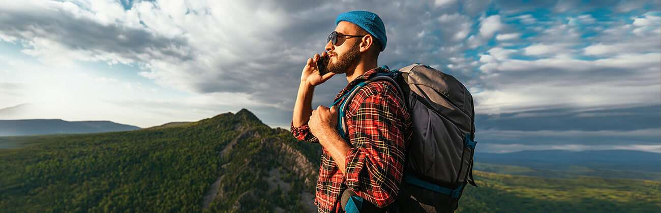 Man uses mobile phone while hiking in wilderness mountains